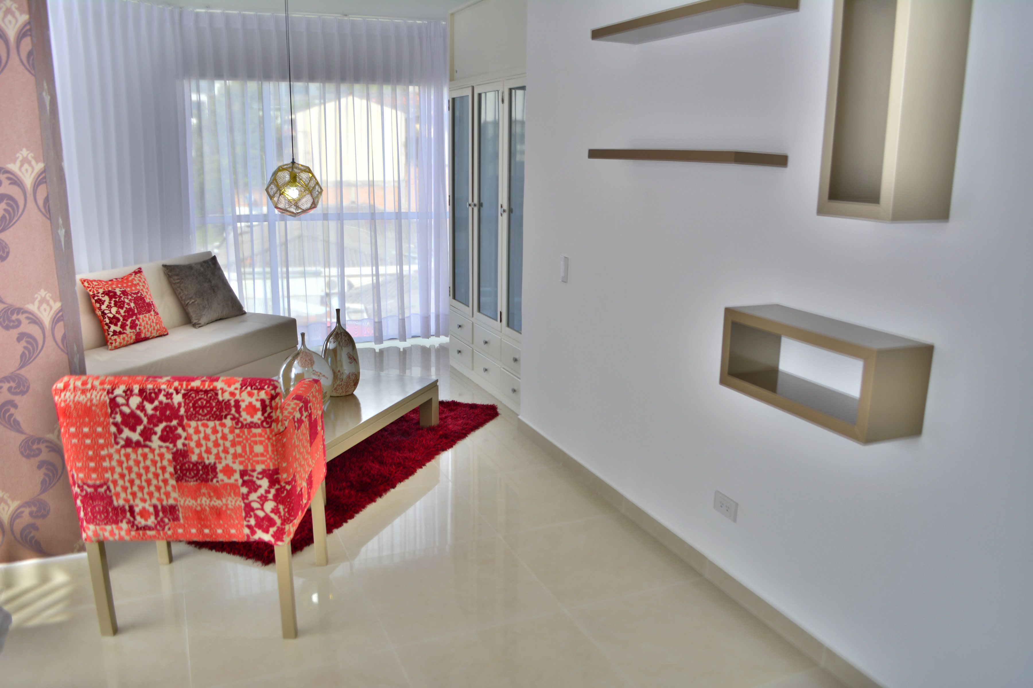Una sala de estar moderna con un sofá, un sillón estampado y una alfombra roja.