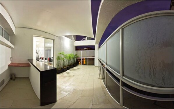 A modern interior with a central counter, a staircase, and a glass wall.