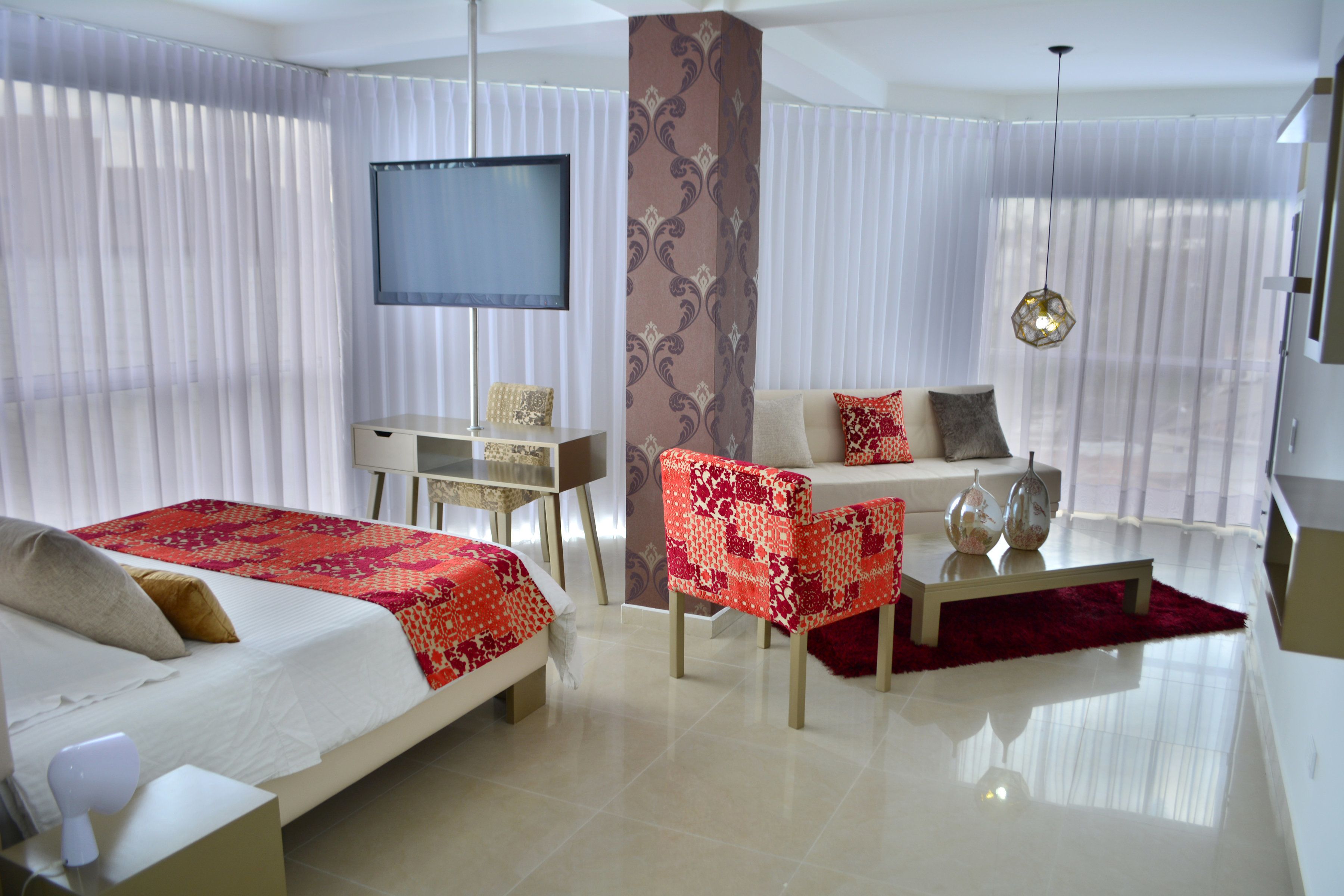 A hotel room with two beds, a desk, a sofa, and a TV.