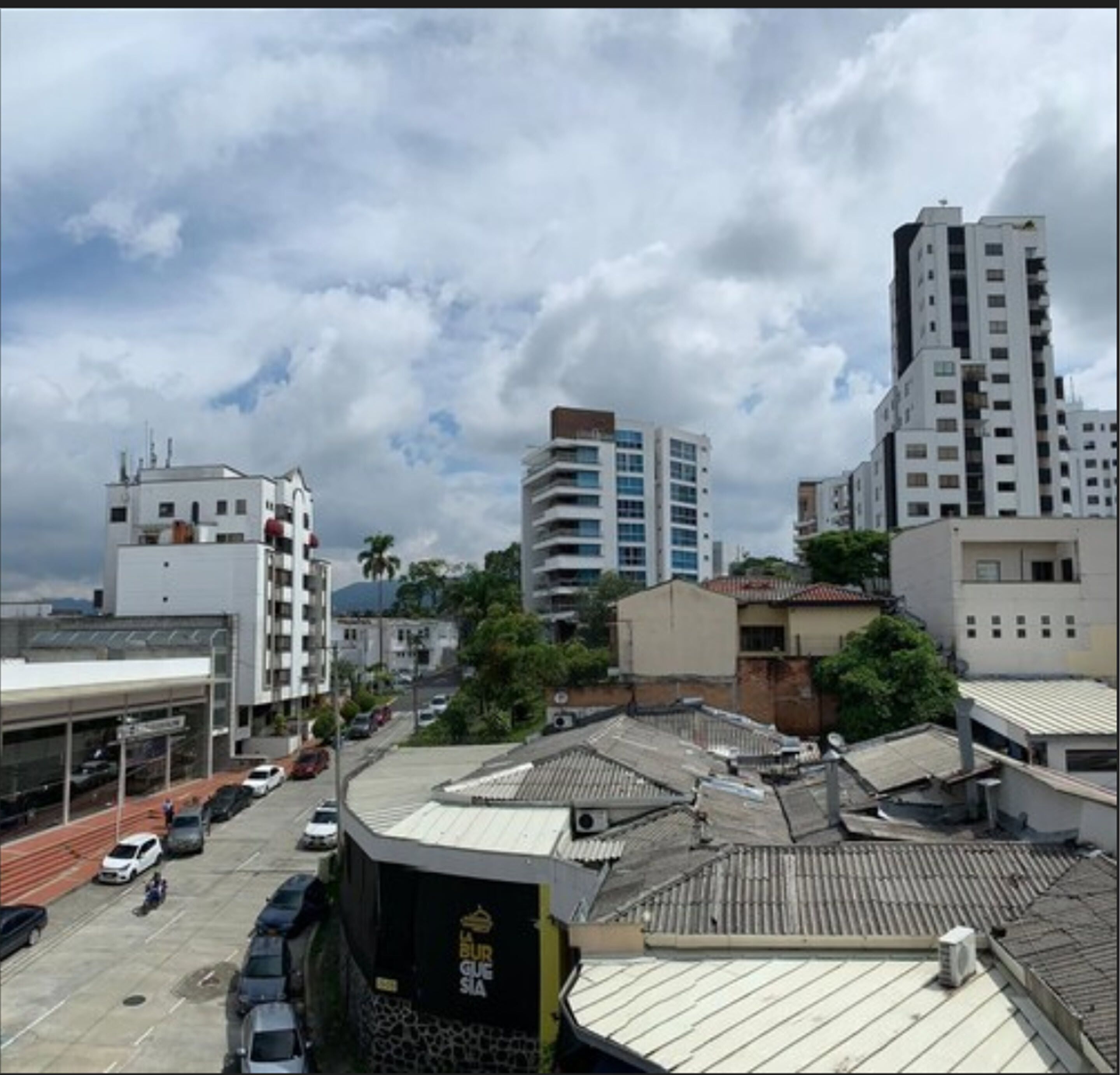A cityscape with modern buildings, a parking lot, and a clear sky.