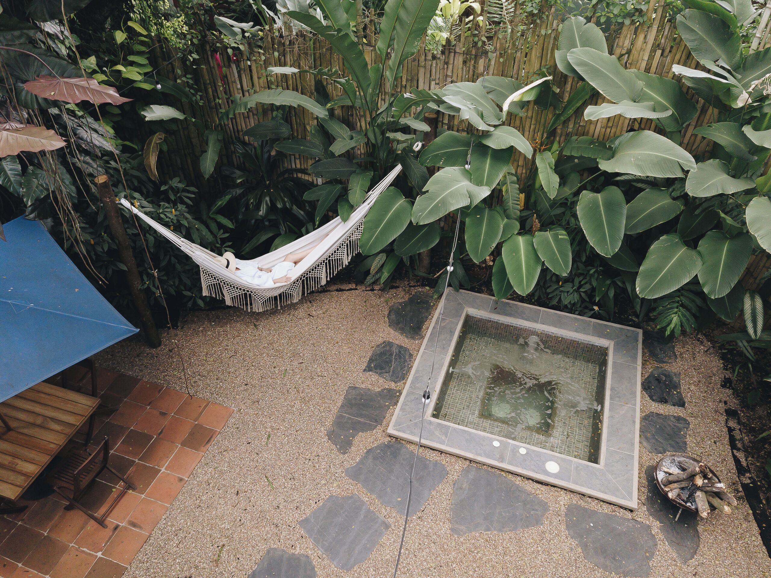 A hammock, a small pool, and a wooden table in a garden area.