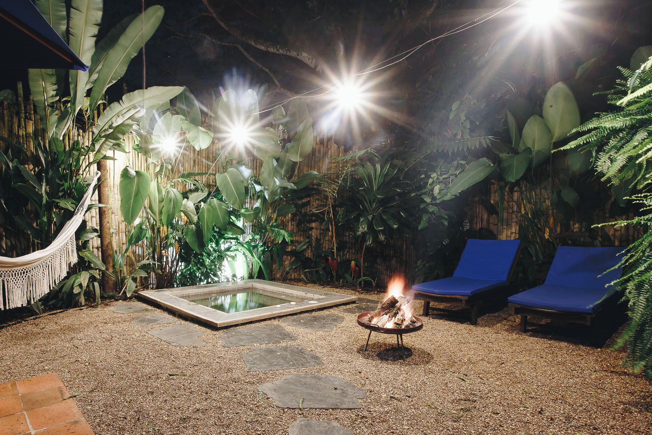 An outdoor area with a fire pit, lounge chairs, and a pool.