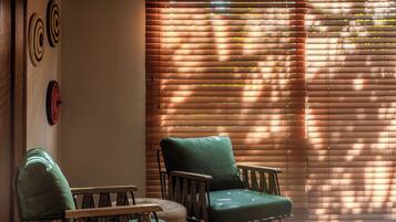 A room with two green armchairs, a woven side table, and a wall with circular wall art.
