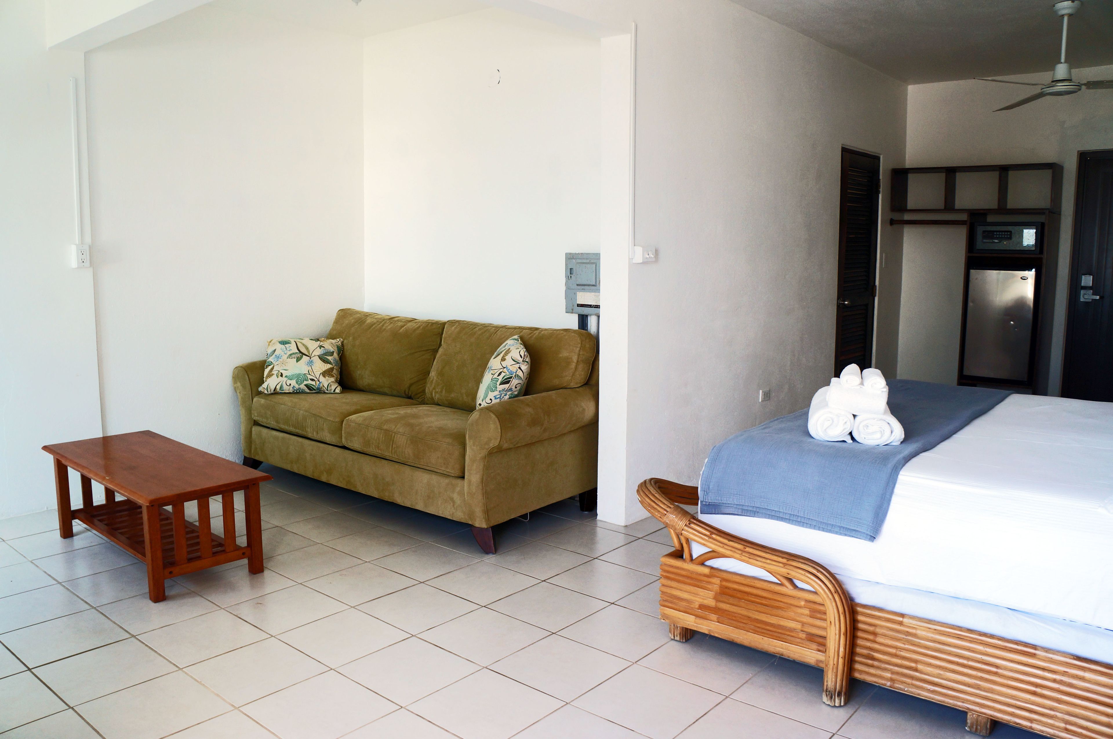 A room with a bed, a wooden bench, a sofa, and a small table.