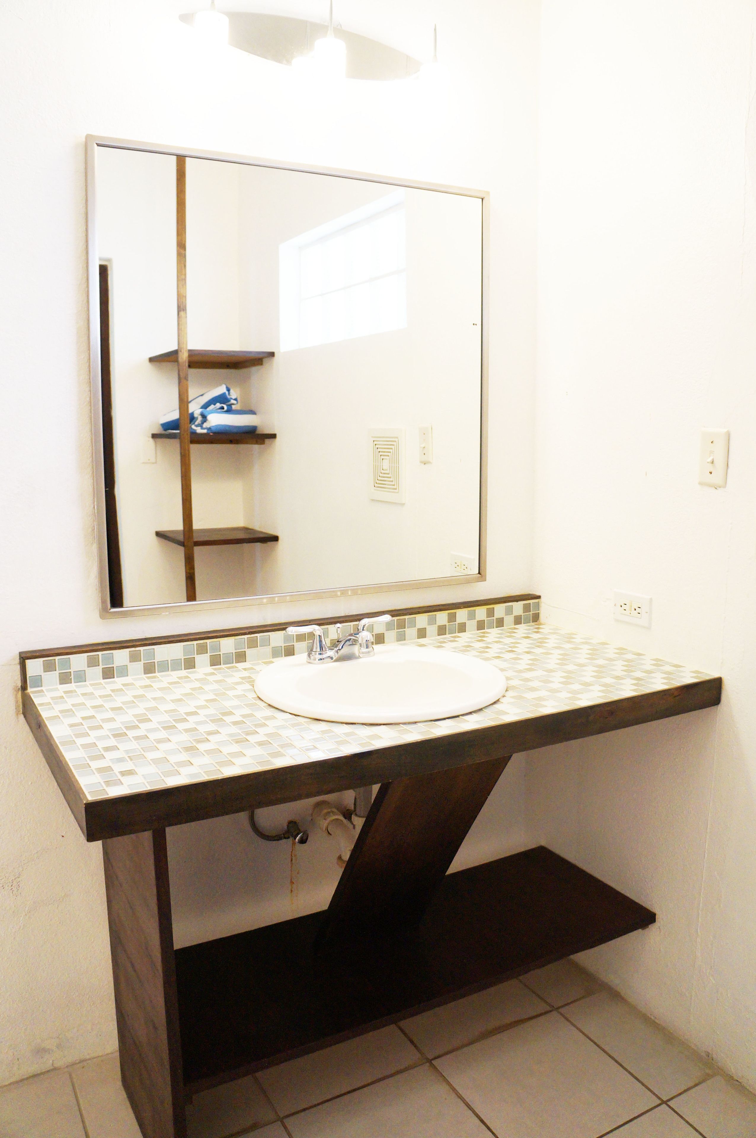 A bathroom with a white sink, a mirror, and a tiled backsplash.