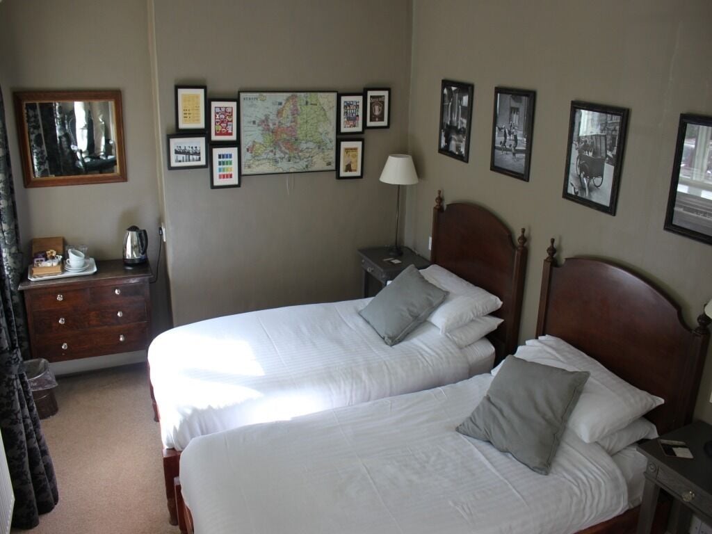 A hotel room with two beds, a dresser, a nightstand, and a map on the wall.