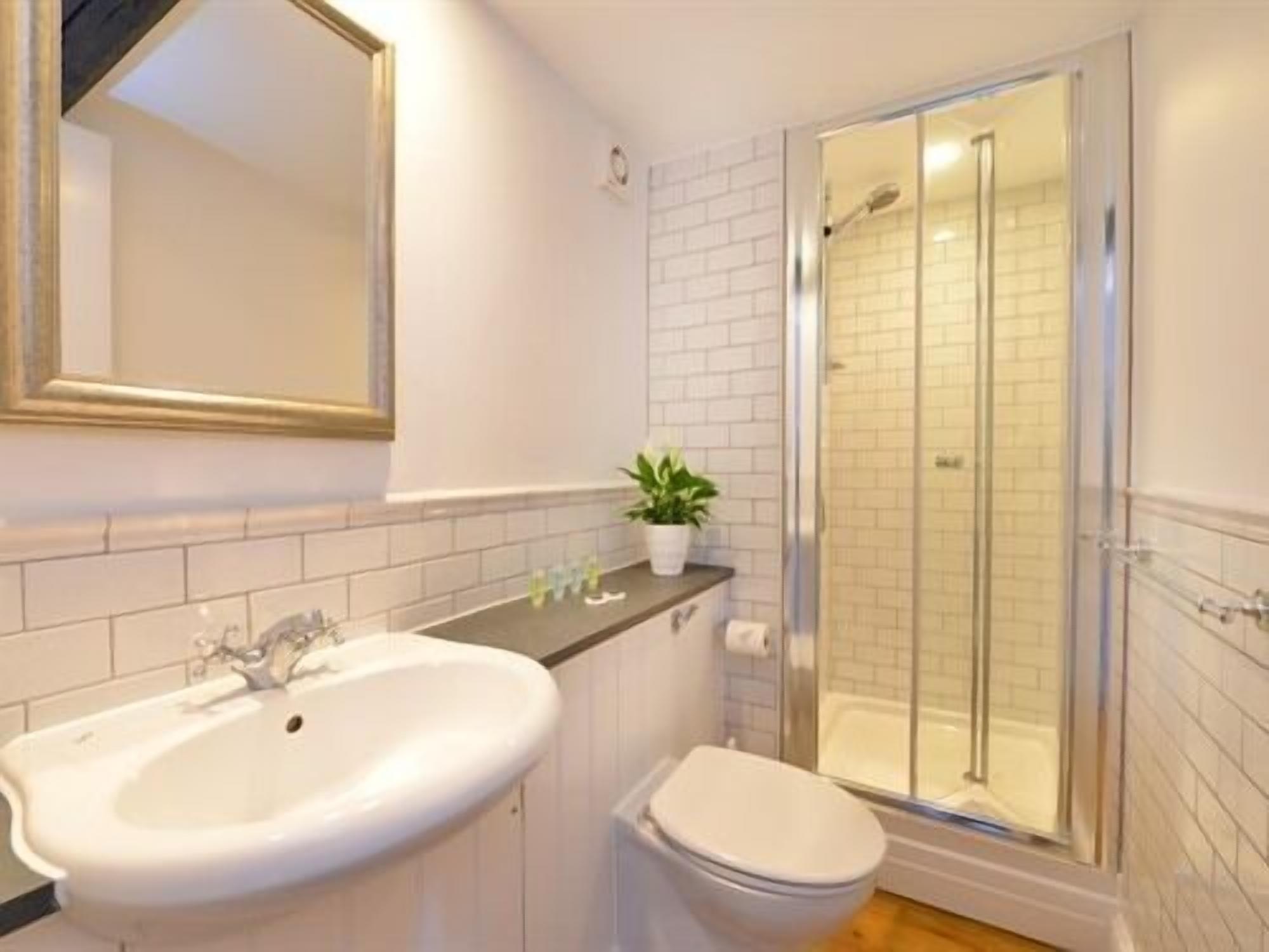 A bathroom with a white sink, toilet, and glass shower enclosure.
