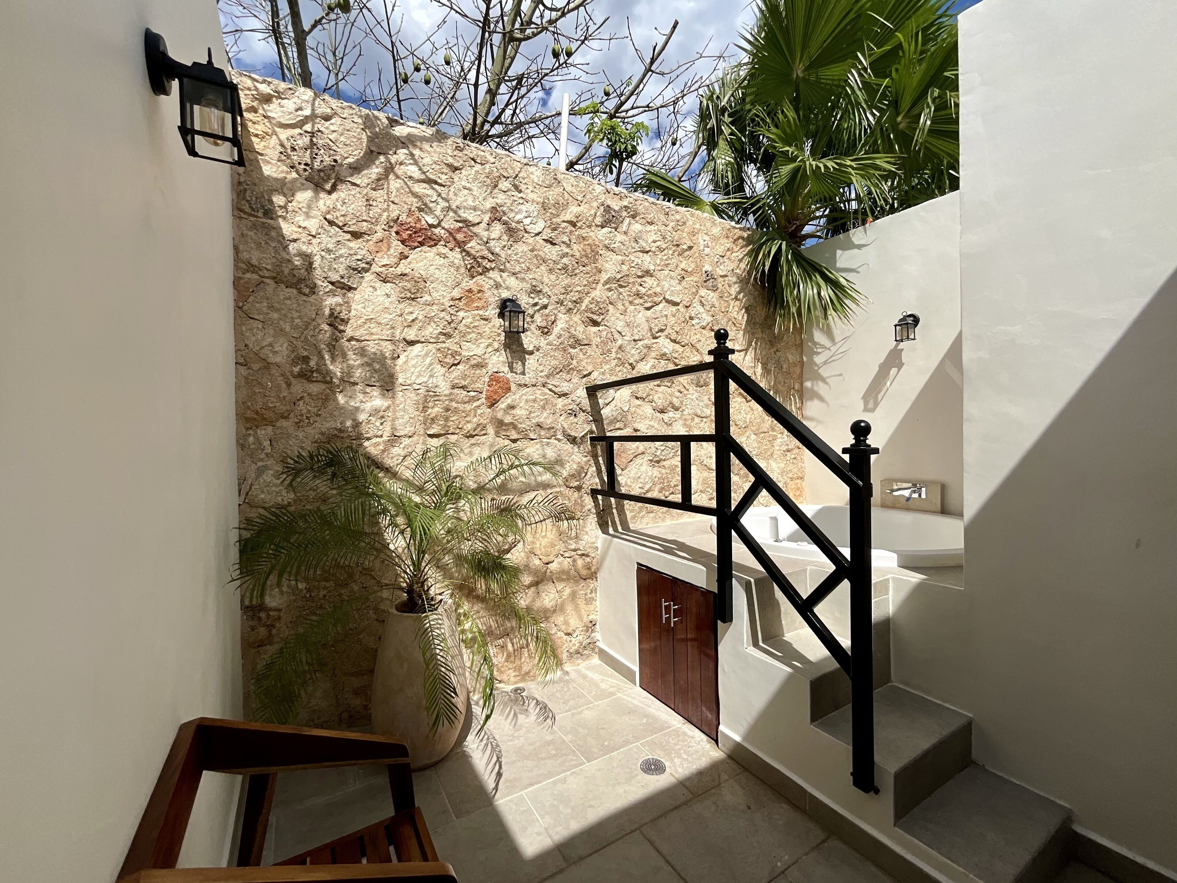 A staircase leading to a door with a stone wall behind it, a potted plant, and a wooden chair.