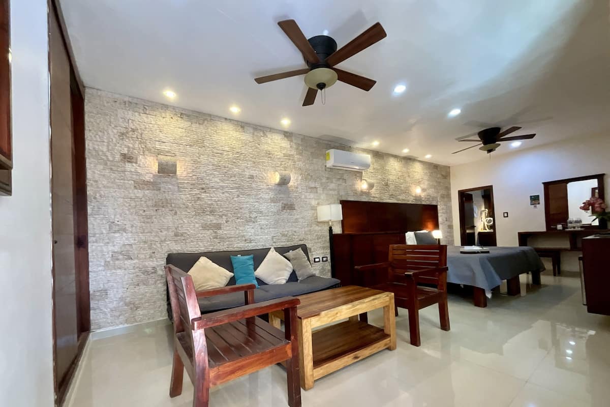 Un salón moderno con pared de textura de piedra, muebles de madera, ventiladores de techo e iluminación empotrada.
