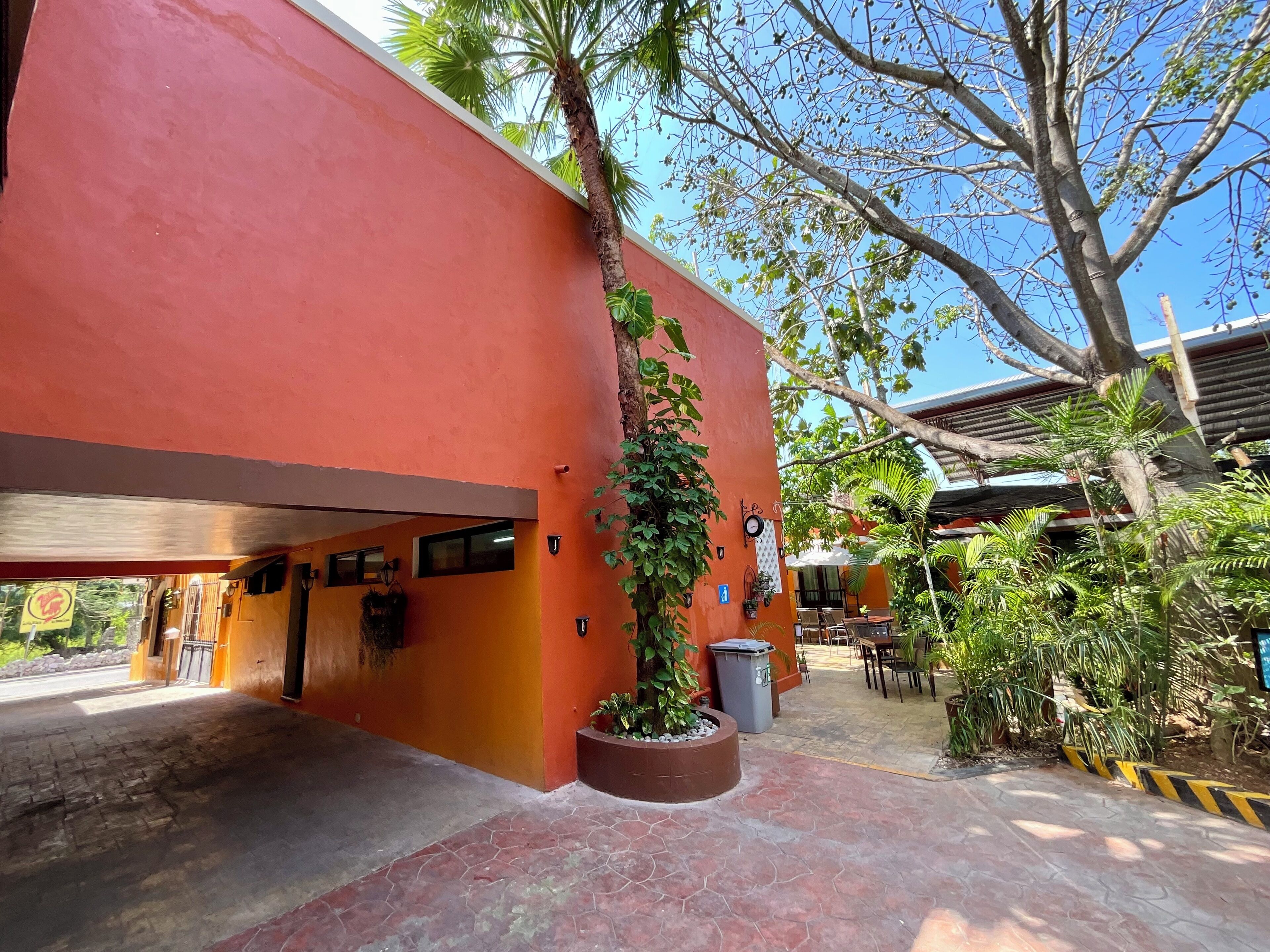 A building with a red exterior, a paved entrance, and outdoor seating.