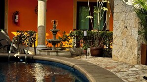 A pool area with a fountain, potted plants, and a fire extinguisher mounted on the wall.