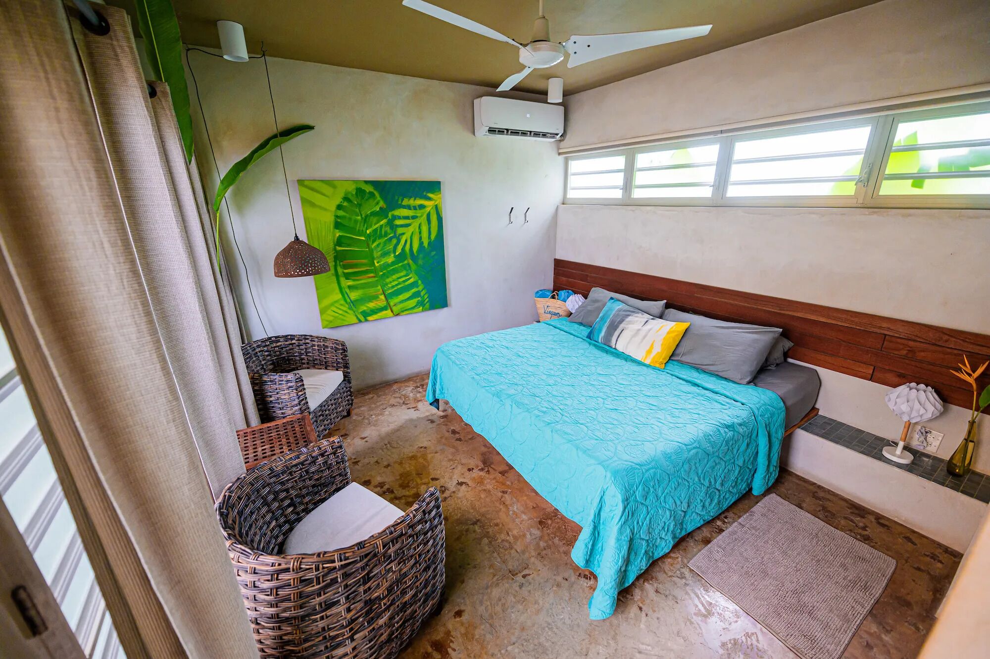A bedroom with a bed, a ceiling fan, a window, and a wall-mounted air conditioner.
