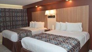 A hotel room with two beds, a patterned curtain, a wall-mounted lamp, and a wooden headboard. - Seahorse Inn (Wildwood)