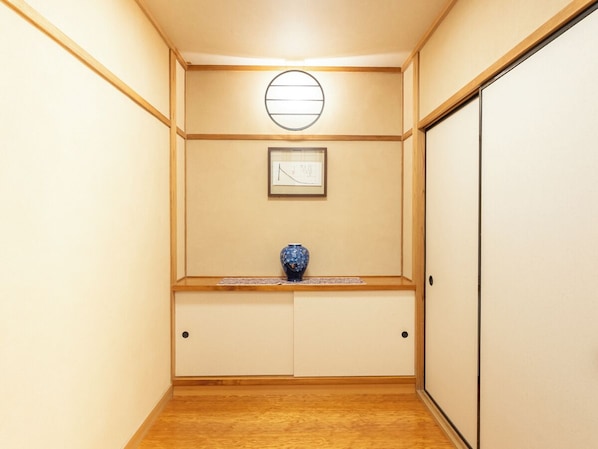 A hallway with wooden flooring, a blue vase on a shelf, a framed picture on the wall, and a sliding door on the right. - LiVEMAX RESORT Jogasaki Kaigan (Ito)