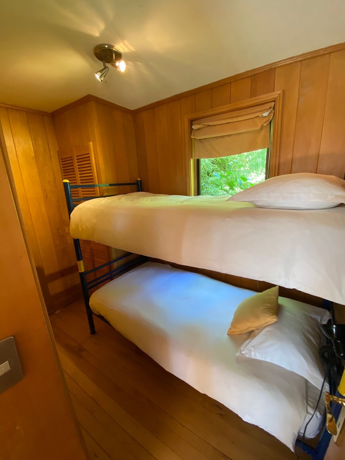 Een slaapkamer met stapelbedden, houten wanden en een raam.