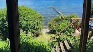 A view from a wooden deck overlooking a body of water with a dock extending into the water.