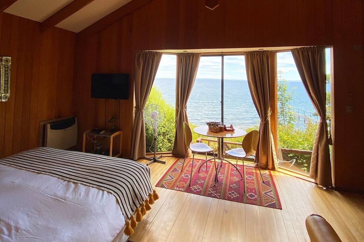 Un dormitorio con una cama grande, televisión, escritorio y vistas al mar.