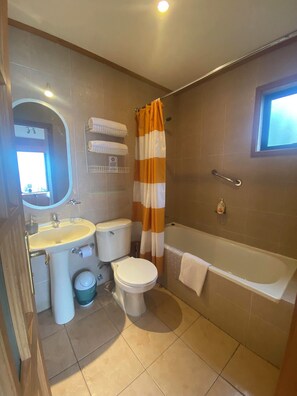 A bathroom with a sink, toilet, and bathtub. There is a shower curtain and a towel rack. - Cabañas Bahía Celeste (Puerto Varas)