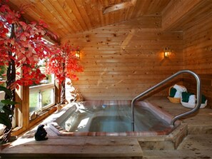 A wooden cabin with a hot tub, wooden walls, and a window with autumn leaves. - Pretty River Valley Country Inn (Grey Highlands)