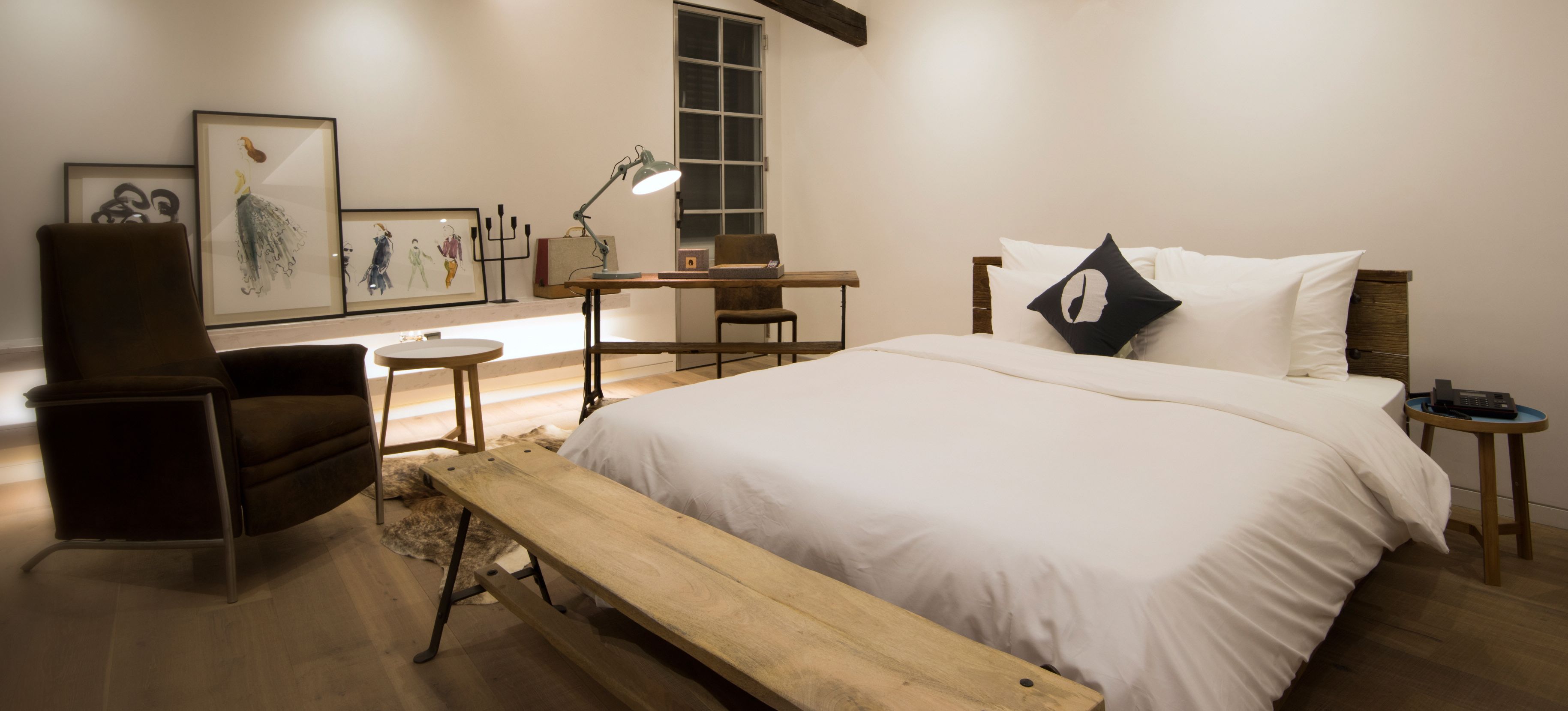 Une chambre à coucher avec un grand lit, un bureau, une chaise et un banc.