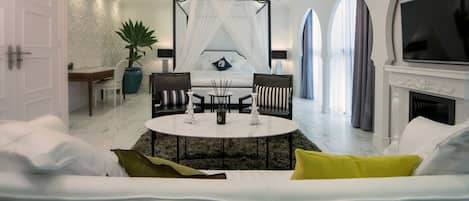 A modern living room with a round coffee table, two armchairs, a sofa, a TV, and a fireplace.
