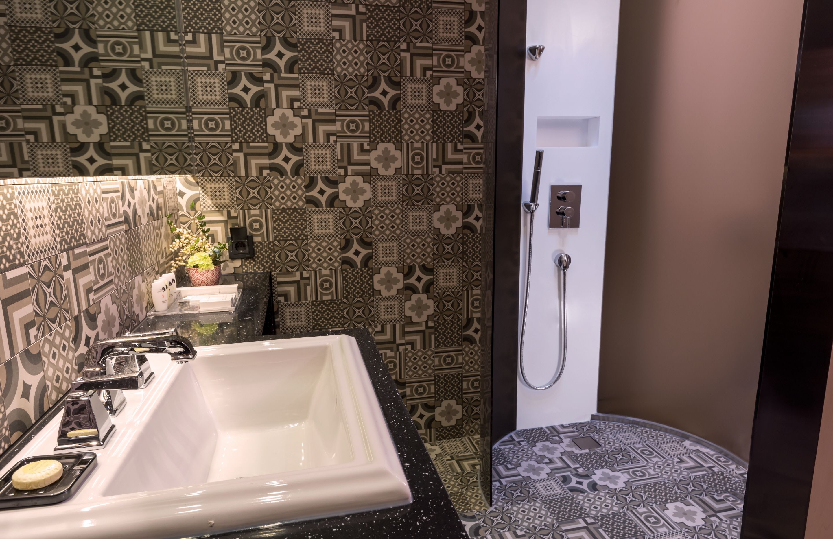 A bathroom with a white sink, a mirror, and a shower area.