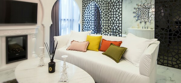 Una sala de estar moderna con un sofá blanco, una chimenea y paneles decorativos en la pared.