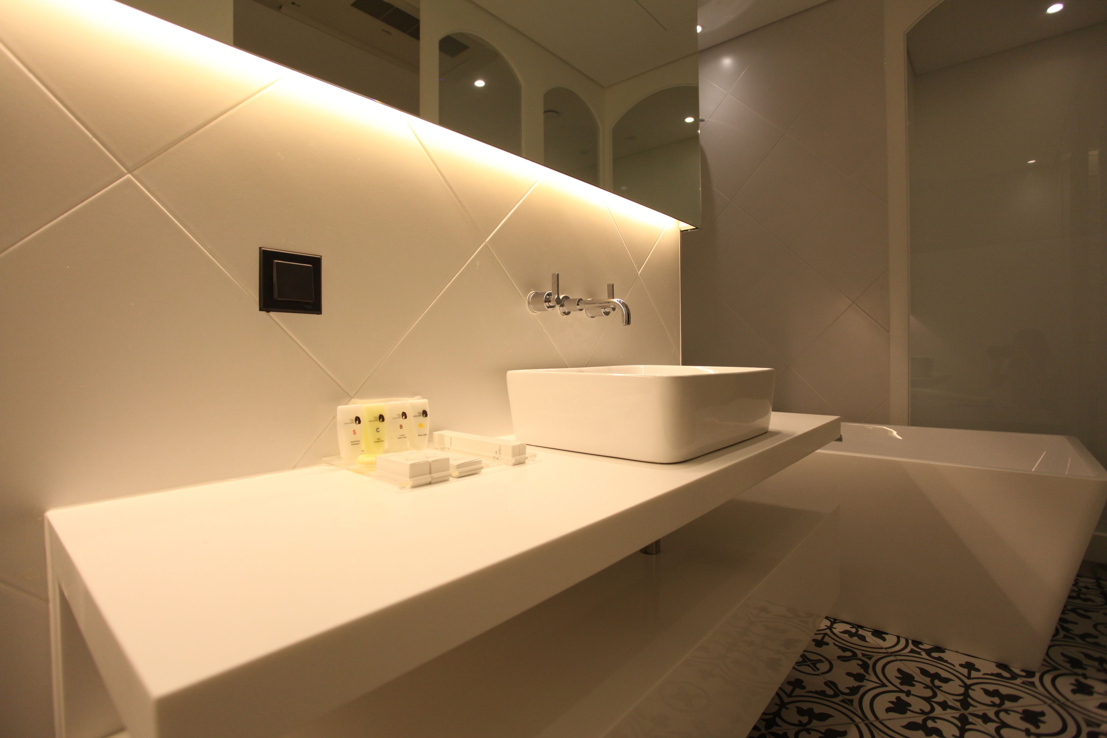 A modern bathroom with a white vanity, a large mirror, and a bathtub.