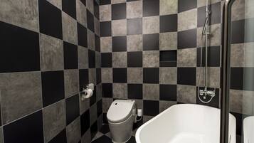A bathroom with a checkered black and gray tile wall, a white toilet, and a white bathtub.
