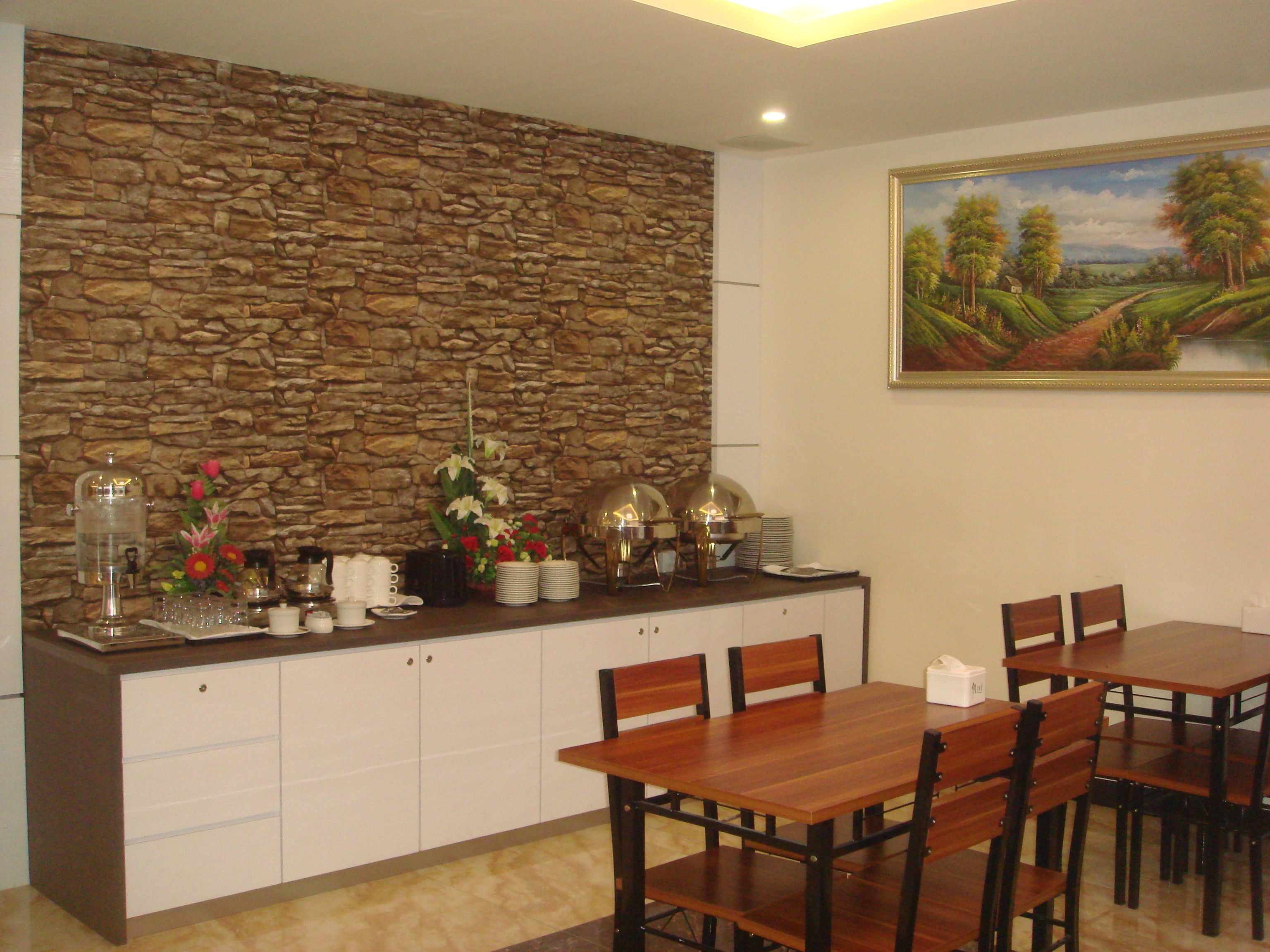 A dining area with a stone wall, a painting, and a buffet setup.