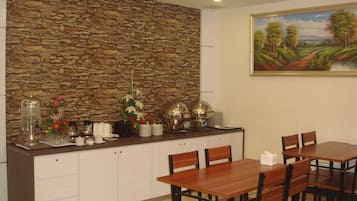 A dining area with a stone wall, a painting, and a buffet setup.