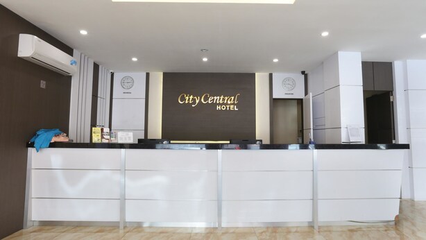 Uma receção de hotel com design moderno, um relógio e um letreiro que diz 'City Central Hotel'.