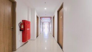A long, well-lit hallway with wooden doors on either side, leading to multiple rooms. - Evora Hotel (Surabaya)
