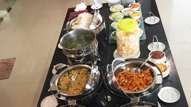 A buffet table with various food items and utensils. - Evora Hotel (Surabaya)
