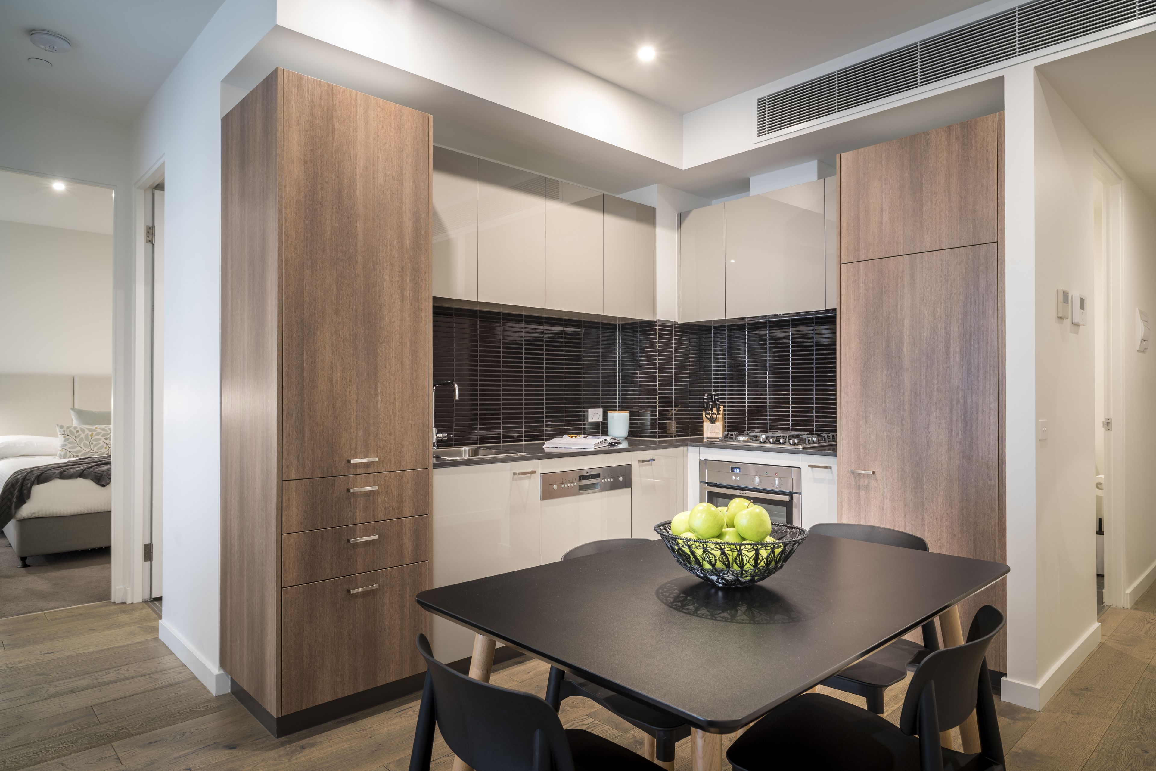 A modern kitchen with wooden cabinets, a black countertop, and a dining table with chairs.
