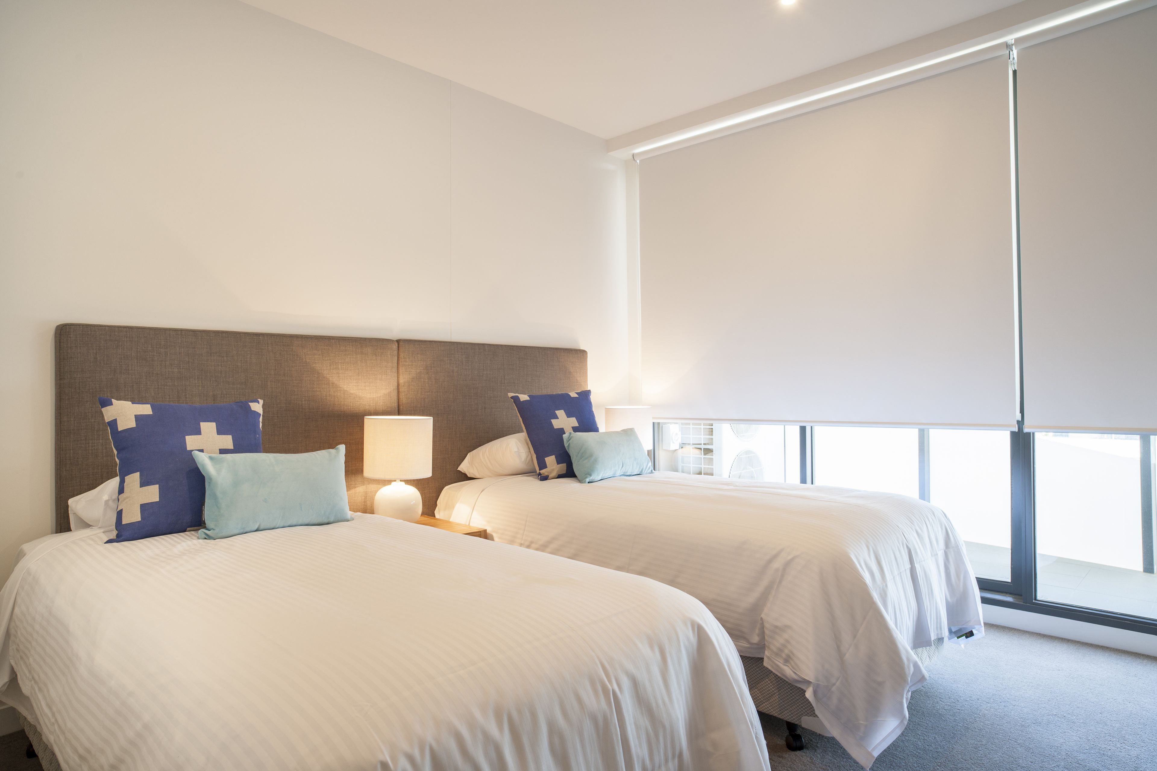 A hotel room with two beds, a large window, and a view of the city.