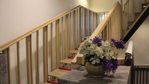 Una escalera con barandillas de madera y un florero sobre una superficie de mármol.