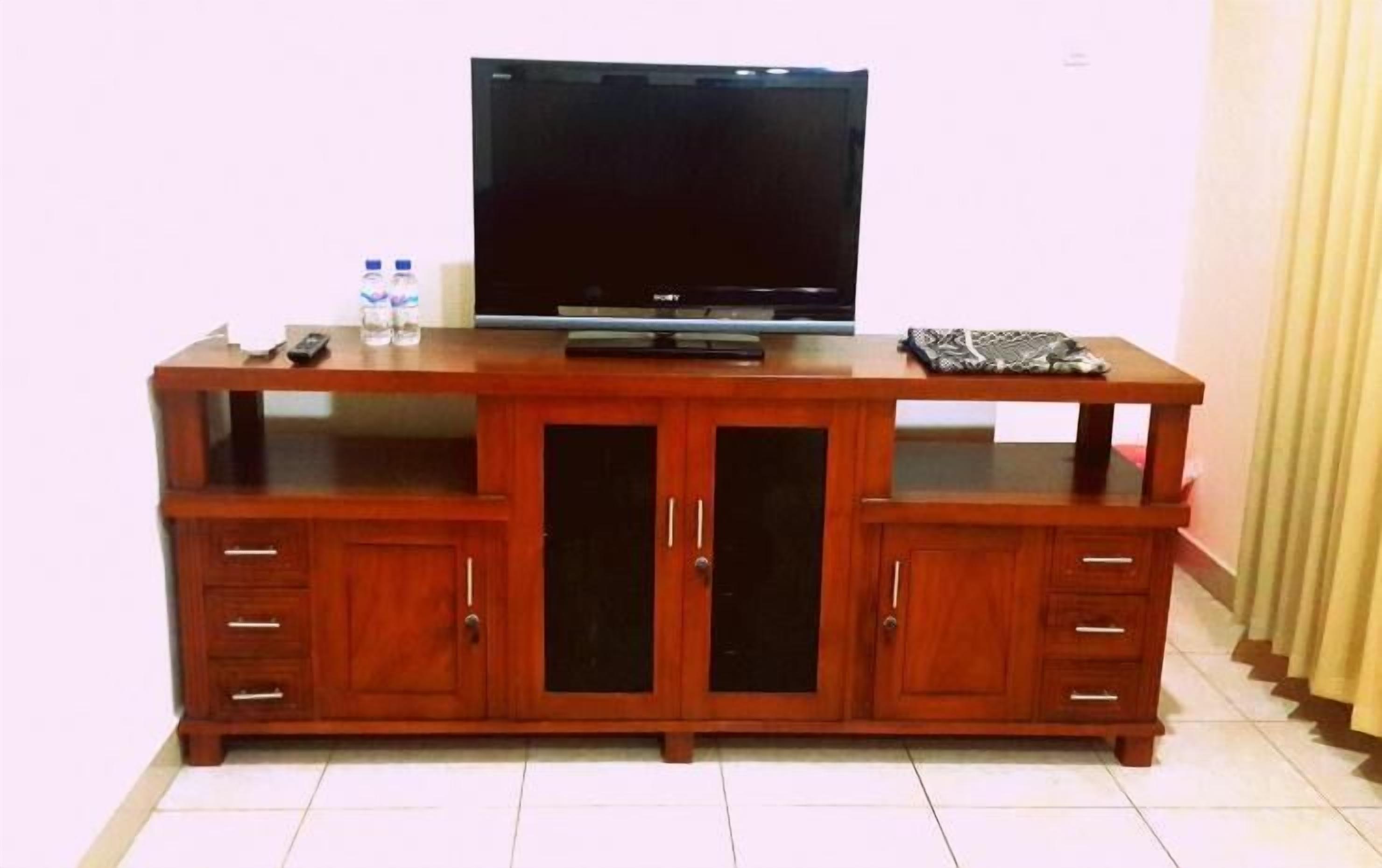 Un mueble de madera con centro de entretenimiento, televisor de pantalla plana, dos cajones y un vitrina de cristal.