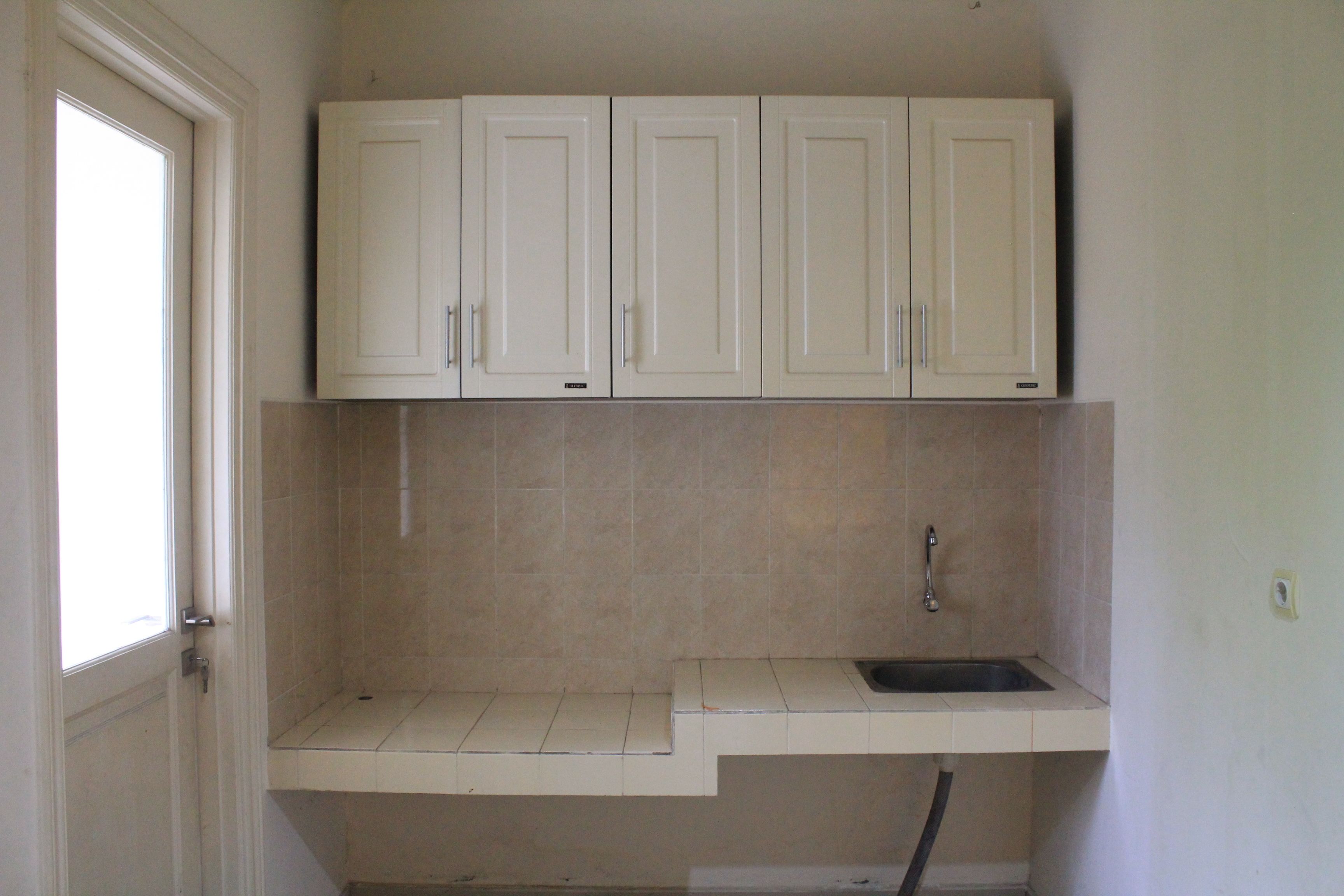 A kitchen with white cabinets, a sink, and a window.