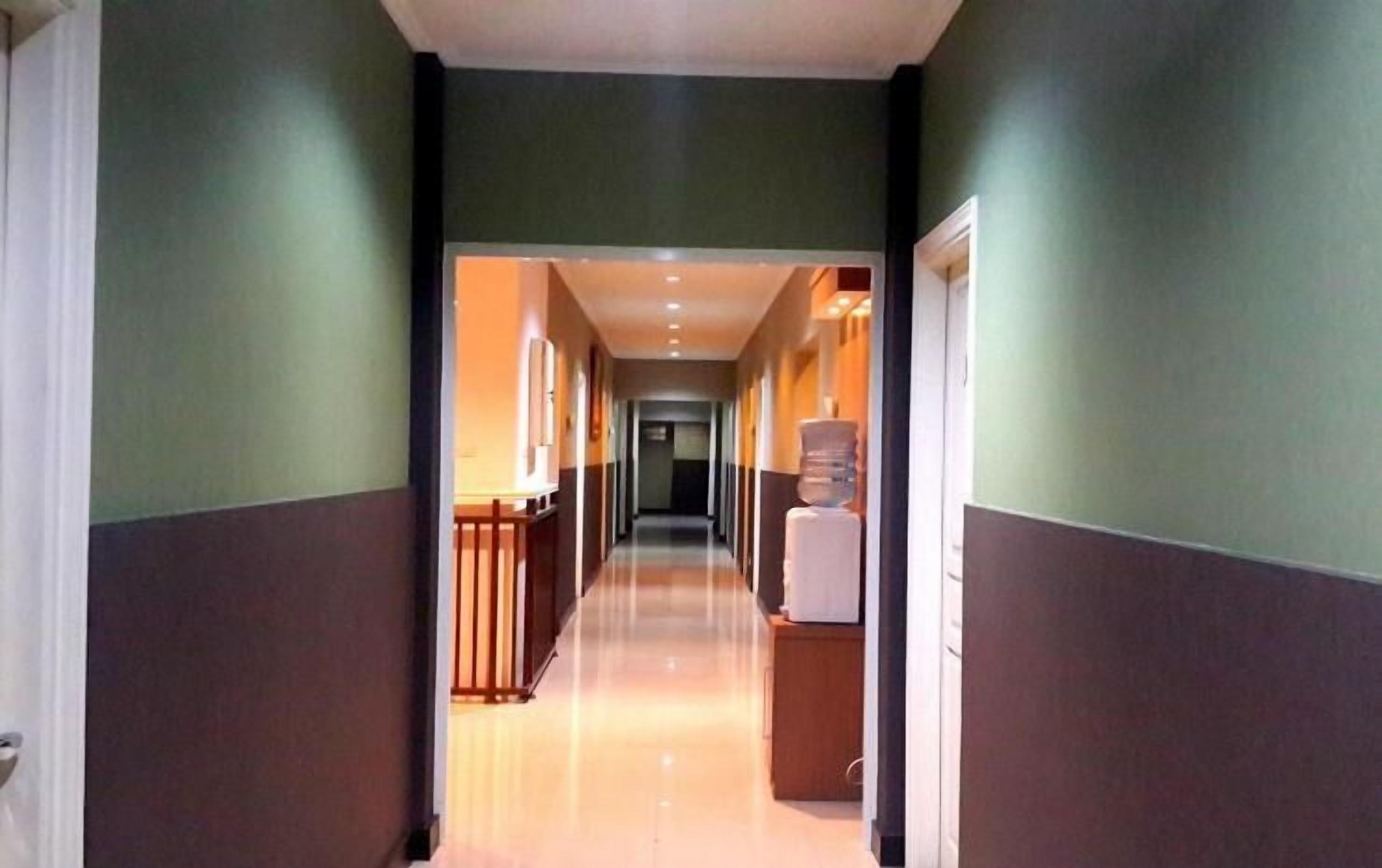 Un pasillo de hotel con barandilla de madera, dispensador de agua y mostrador de recepción.