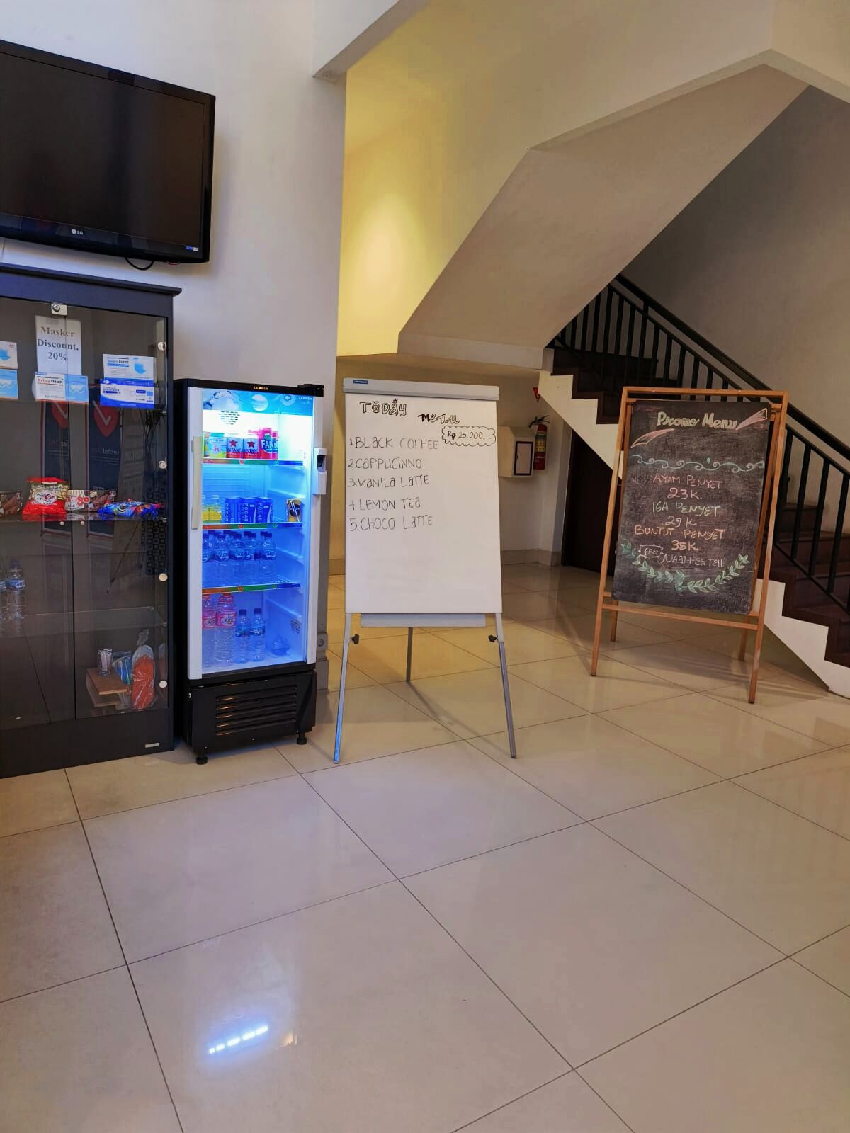 A vending machine with a selection of beverages, a whiteboard with a menu, and a chalkboard with a promotional menu.