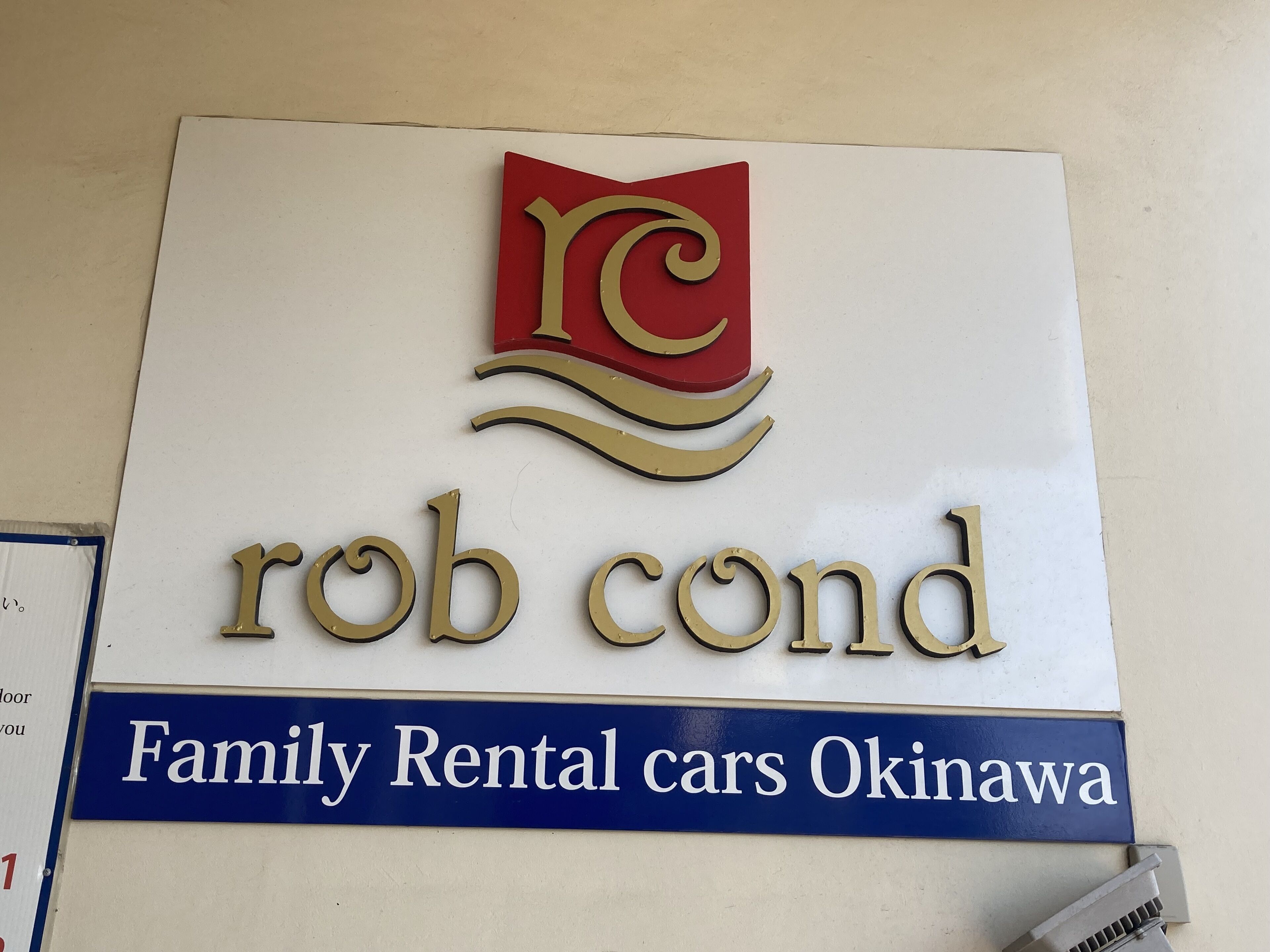 Placa para 'rob cond Family Rental cars Okinawa' com um logotipo acima do texto.