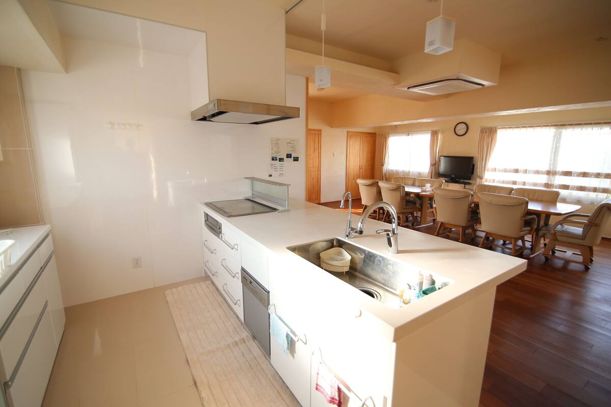 A modern kitchen with a central island, built-in appliances, and a dining area with a TV and seating.