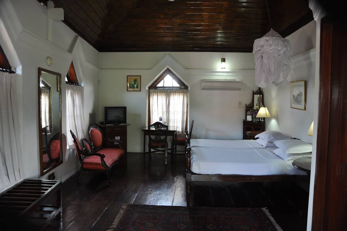 A room with a bed, a desk, a chair, and a television.