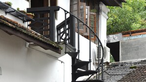 A spiral staircase leading to a balcony with potted plants and a small garden area. - The Old Courtyard Hotel (Kochi)