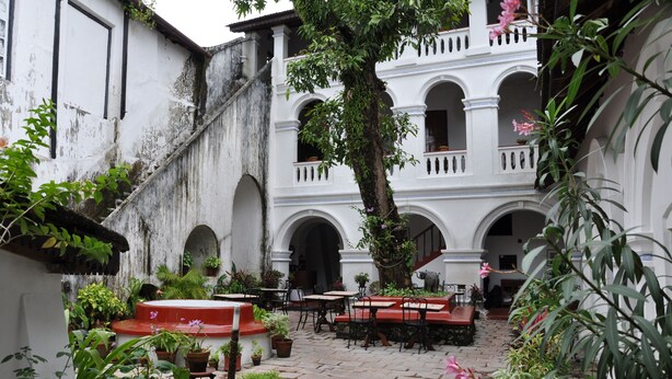 A courtyard with outdoor seating, potted plants, and a staircase leading to an upper level. - The Old Courtyard Hotel (Kochi)