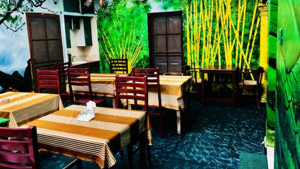 Un restaurante con decoración de bambú, mesas y sillas de madera y un piso de baldosas.