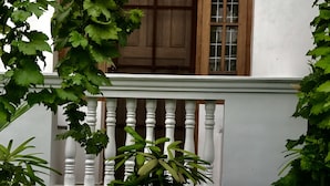 Un edificio blanco con un balcón que presenta una puerta de madera y paneles de vidrio.