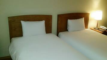 Two single beds with wooden headboards in a hotel room.