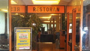 A hotel entrance with a sign for the restaurant and breakfast area. - Plaza Hotel Harco Mangga Dua (Jakarta)